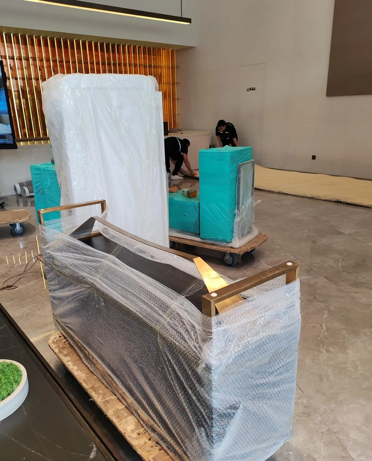 商业空间物品打包搬运现场，家具使用气泡膜与缠绕膜防护