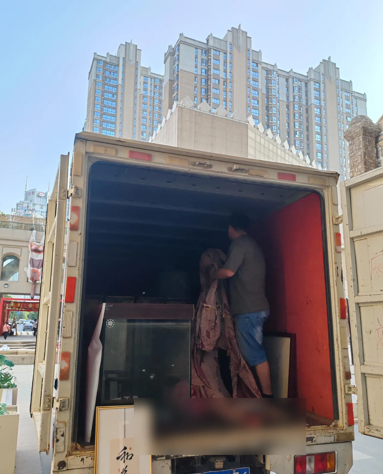 搬运人员在楼栋旁人工卸车搬运大件家具